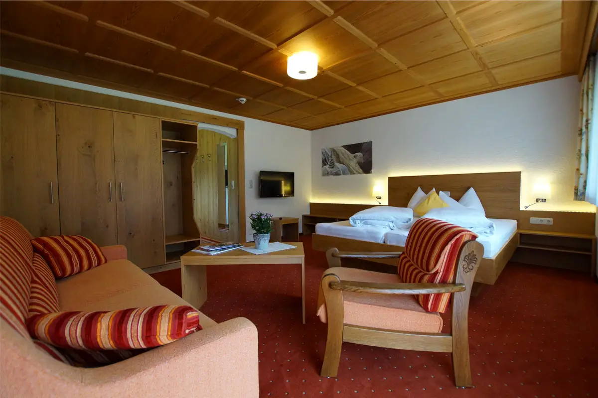 Wohnschlafzimmer mit Doppelbett, Couch und Holzdecke