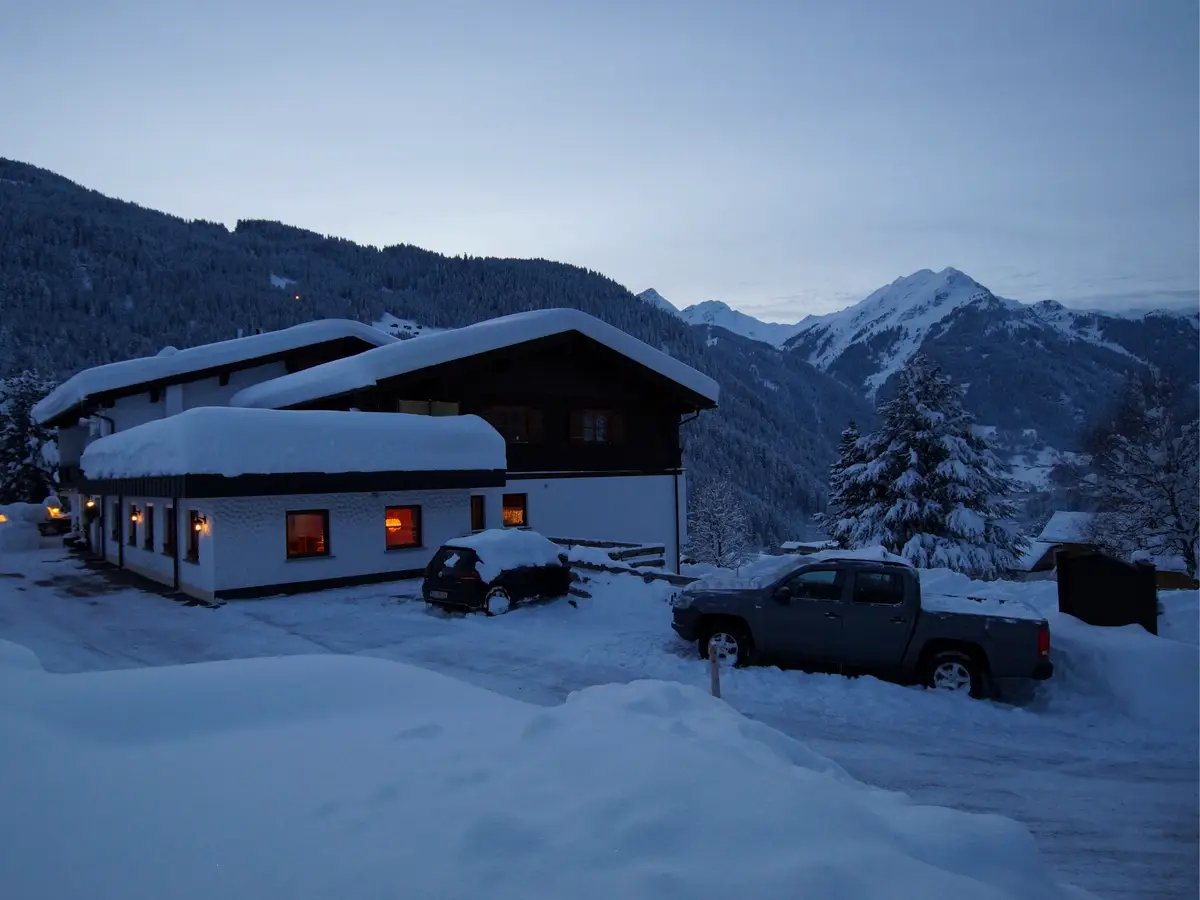 Das Haus Matschun im Schnee zur blauen Stunde, die Fenster beleuchtet