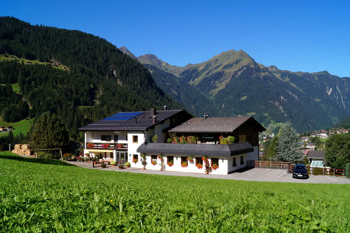 Das Haus Matschun über der Sommerwiese, dahinter die Berge